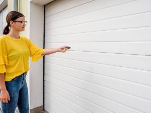 Woman holding a garage door remote next to her garage door exterior