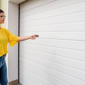 Woman holding a garage door remote next to her garage door exterior
