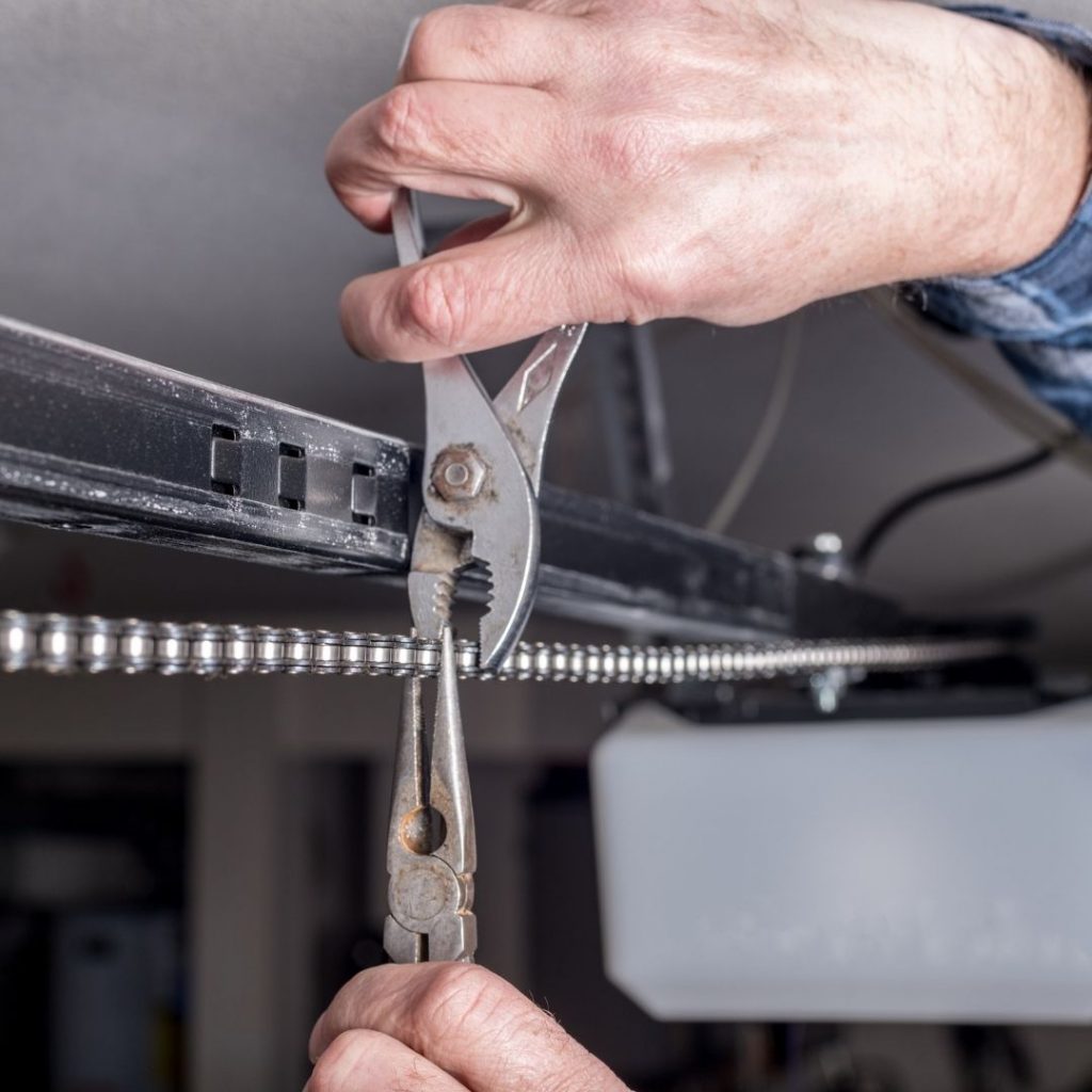 technician repairs the garage door chain