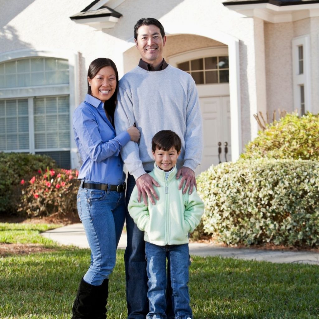 family happily standing in front of their home